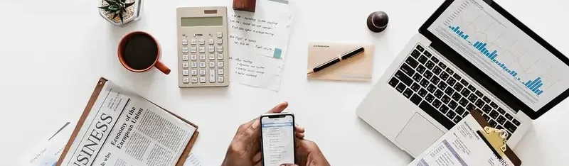 Werkplek van bovenaf met laptop, rekenmachine, koffie en smartphone
